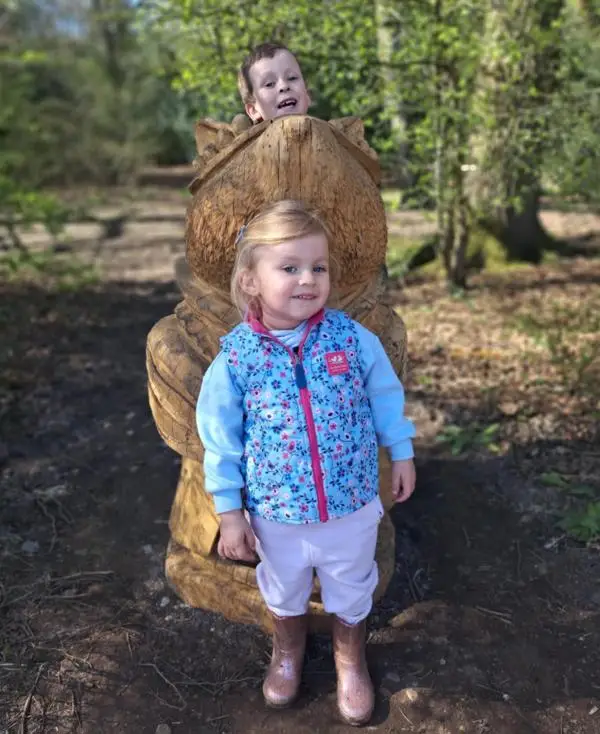 Two children with a carved oak sculpture of a Brambly Hedge mouse.