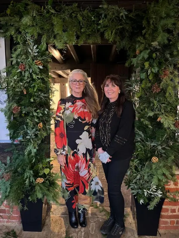 Chair, Caroline Haines, and florist Victoria standing under a greenery arch.