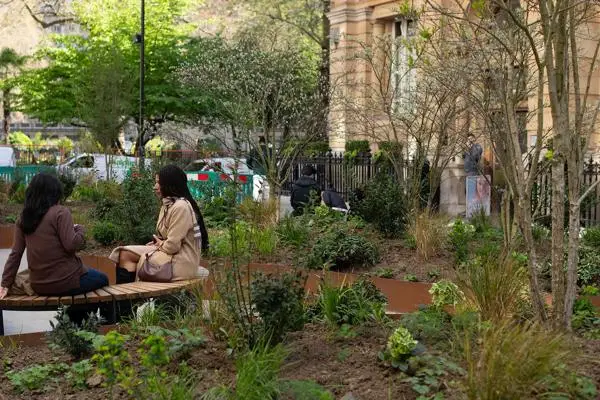 People sitting on a wooden bench within the Finsbury Circus Western Arm project area. 
